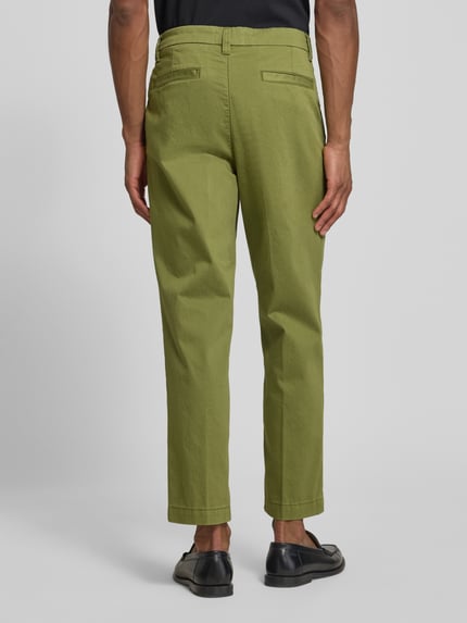 Männermodel trägt Regular Fit Chino aus katoenmix model 'TAAMIR PLEATED' van Armedangels, look: effen, achterzakken, riemlussen, sluiting met haakje en verborgen ritssluiting, zijzakken, gestikt logo, groen, textuur glad, ganzebodyaanzicht achterkant.