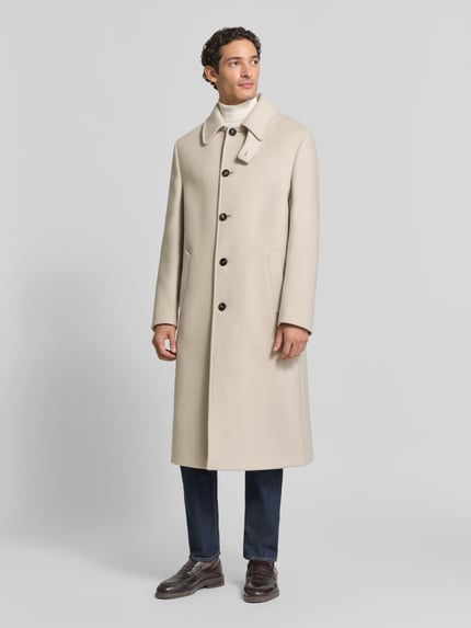 Männermodel trägt Regular Fit Mantel mit Eingrifftaschen von bugatti in Beige, Schurwoll-Mix, Umlegekragen, Knopfleiste, Ganzkörperansicht von vorne.
