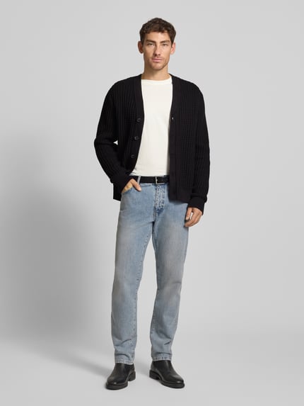 Männermodel trägt Herren Strickjacke aus reiner Baumwolle Modell 'TOM' von SELECTED HOMME, unifarben, Waffelstruktur, Ganzkörperansicht von vorne.