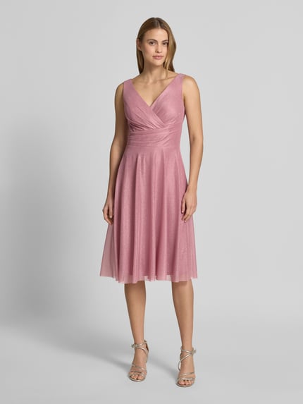 Vrouwenmodel draagt knielange cocktailjurk met V-hals van TROYDEN COLLECTION, chiffon, getailleerd model, brede bandjes, Ganzkörperansicht von voren.