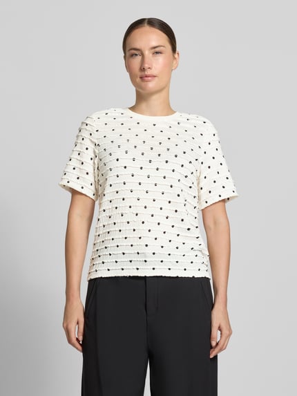 Frauenmodel trägt Boxy Fit T-Shirt mit Allover-Muster von Jake*s Casual in Weiß mit schwarzen Punkten, strukturierte Oberfläche, Ganzkörperansicht von vorne.
