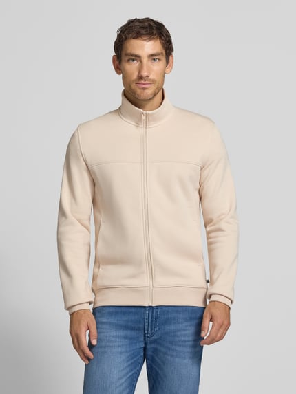 Männermodel trägt Regular Fit Sweatjacke aus Baumwoll-Mix von s.Oliver RED LABEL in Beige mit glatter Struktur, Ganzkörperansicht von vorne.