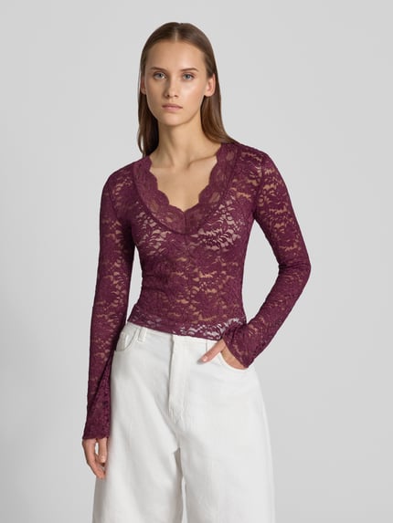 Frauenmodel trägt Slim Fit Langarmshirt in Spitzen-Mesh-Optik Modell 'NIKKA' von ONLY in Dunkelrot mit transparenter Spitze, Nahaufnahme Oberkörper, Damen Langarmshirt von ONLY.