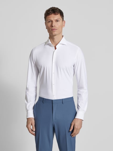 Männermodel trägt Slim Fit Business-Hemd mit Kentkragen van JOOP! Collection, materiaalmix met stretch, knoopsluiting, langemouwen, afgeronde zoom, ruglengte 70 cm, schouderbreedte 46 cm, mouwlengte 69 cm, effen wit, gladde textuur, Ganzkörperansicht van voren.
