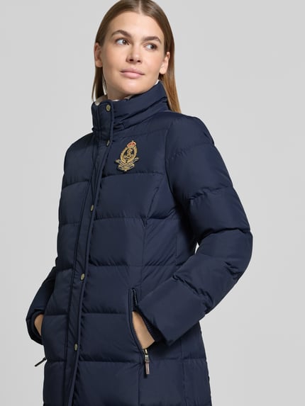 Frauenmodel trägt Steppmantel mit Kapuze von LAUREN RALPH LAUREN in Dunkelblau, unifarben, Logo-Stitching, Nahaufnahme Oberkörper.