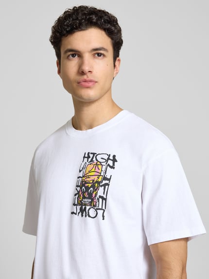 Männermodel draagt wit T-shirt met print, relaxed fit van puur katoen, model 'HATTY MAN' van Edwin, ronde hals, nahaufnahme bovenlichaam.