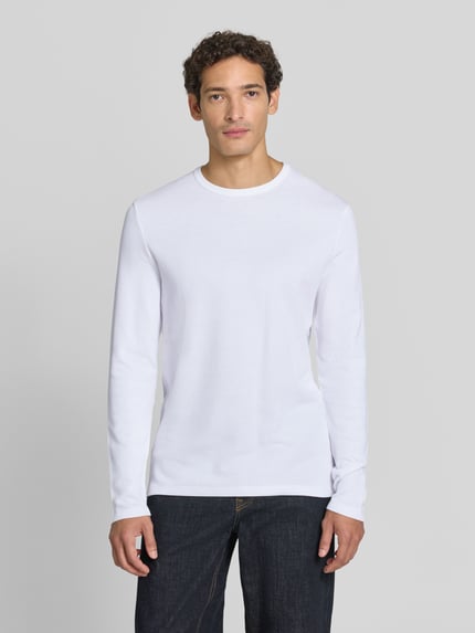 Männermodel trägt Regular Fit Longsleeve aus reiner Baumwolle Modell 'Basic' von Lindbergh in Weiß, Ganzkörperansicht von vorne, Herren Longsleeve, Rundhalsausschnitt, Rückenlänge bei Größe M 73 cm.