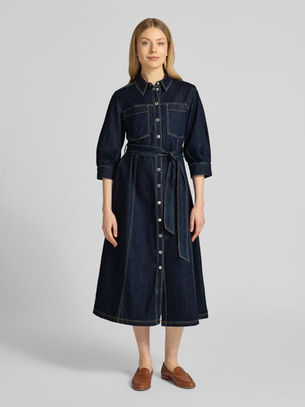 Vrouwenmodel draagt Hemdblusenkleid mit Bindegürtel van Betty Barclay in denimlook, mix van katoen en lyocell, A-lijn midi-jurk met overhemdkraag, knoopsluiting, strikceintuur, ruglengte maat 36: 121 cm, borstwijdte: 51 cm, mouwlengte: 43 cm. Volledig frontaal lichaamsaanzicht.