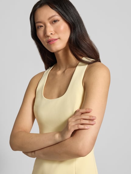 Frauenmodel trägt Abendkleid mit Viskose-Anteil Modell 'Melva' von Forever New in Hellgelb, Karree-Ausschnitt, Nahaufnahme Oberkörper.