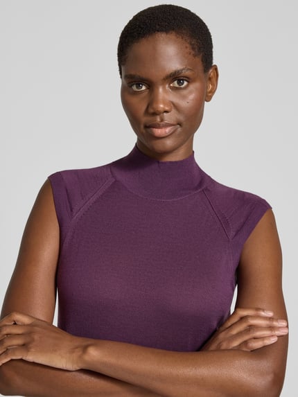 Frauenmodel trägt Pullunder aus Wolle mit Mock Neck von BOSS in unifarbener, matter Strickoptik mit Strukturmuster, Nahaufnahme Oberkörper.