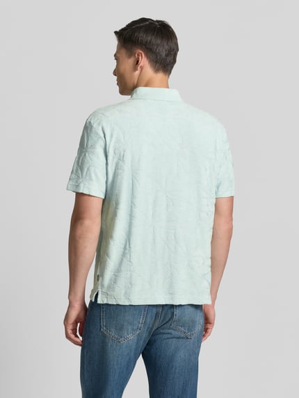 Männermodel trägt Regular Fit Poloshirt aus Baumwoll-Mix Modell 'PE_FLOWER' von BOSS Orange, Optik:Allover-Muster, Struktur, Ganzkörperansicht Rückansicht.