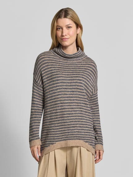 Frauenmodel trägt Oversized Fit Strickpullover mit Viskose-Anteil von Apricot, gestreift, mit verlängertem Rücken, Nahaufnahme Oberkörper.