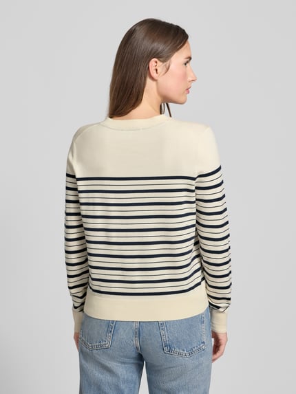 Frauenmodel trägt Regular Fit Strickjacke aus Baumwoll-Mix von Tommy Hilfiger mit gestreiftem Allover-Muster in Beige und Dunkelblau, Feinstrick, Rückansicht Ganzkörperansicht.