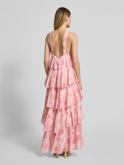 Frauenmodel trägt Volant Abendkleid mit V-Ausschnitt Modell 'FELICIA' von Vero Moda, rosa, aus Chiffon, Maxi-Länge, Ganzkörperansicht Rückansicht.