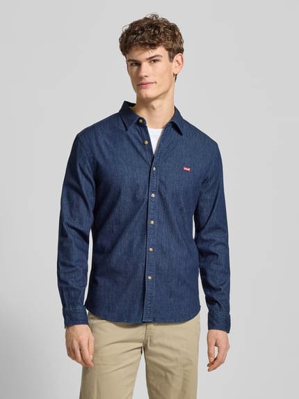 Männermodel trägt Freizeithemd in Denim-Optik von Levi's®, dunkelblau, Baumwoll-Mix mit Stretch-Anteil, Regular-Fit, Kentkragen, Knopfleiste, Label-Stitching, Ganzkörperansicht von vorne.