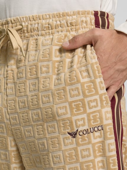 Männermodel trägt Straight Fit Sweatpants mit Label-Stitching von COLUCCI, cremefarben mit geprägtem Muster und Tunnelzug, Nahaufnahme Oberkörper.