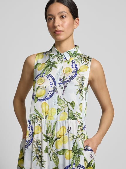 Frauenmodel trägt Hemdblusenkleid aus Reine Viskose mit Taillierter Schnitt, Midikleid, Hemdblusenkragen, Knopfleiste, Stufenrock von Marc Cain, Motiv mit Zitronen und Blättern, Ganzkörperansicht von vorne, Rückenlänge bei Größe 36: 116 cm, Brustweite bei Größe 36: 50 cm, Ärmellänge bei Größe 36: 9 cm.