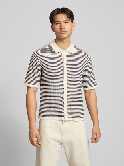 Männermodel draagt Regular Fit vrijetijdsoverhemd met 1/2-mouwen van Jack & Jones in zwart-wit gestreept puur katoen, polokraag, knoopsluiting, ruglengte maat M 67 cm, schouderbreedte 58 cm, mouwlengte 28 cm, ganzekörperansicht van voren.