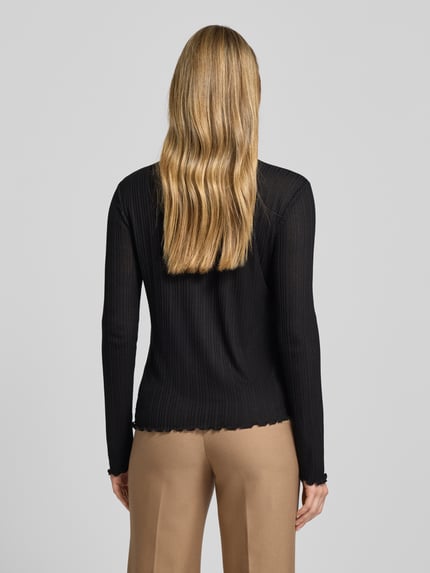 Männermodel trägt Longsleeve mit Stehkragen Modell 'Sivi' von OPUS, czarny, prążkowana tekstura, Slim Fit, muszlowy brzeg, widok z tyłu, kontekst: damski longsleeve OPUS, mieszanka wiskozy, długość tyłu 60 cm przy rozmiarze 36. Ganzkörperansicht Rückansicht.