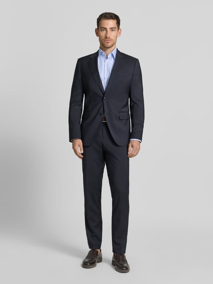 Männermodel trägt Slim Fit Anzugsakko aus reiner Schurwolle Modell 'H-HUGE-263' von BOSS, dunkelblau, Allover-Muster, Ganzkörperansicht von vorne.