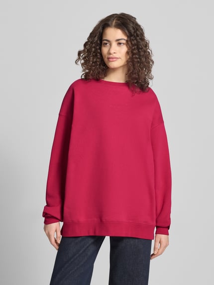 Frauenmodel trägt Oversized Sweatshirt mit Logo-Stitching Modell 'Toast' von OH APRIL, satter Rotton, Baumwoll-Mix, Ganzkörperansicht von vorne.