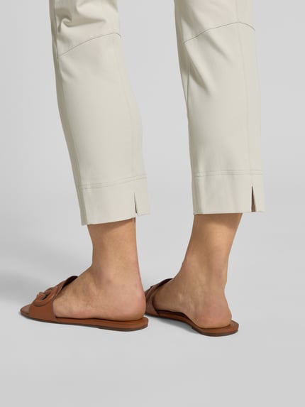 Frauenmodel trägt Schmale Schlupfhose aus Techno Cotton Superstretch von Raffaello Rossi, Slim-Fit, verkürzte Passform, Modell 'PENNY 6/8', helle Farbe, glatte Textur, Detailaufnahme Unterschenkel von hinten, Bundweite 36 cm, Innenbeinlänge 61 cm.