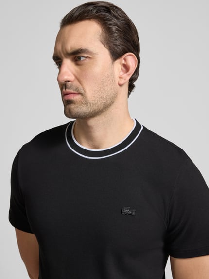 Männermodel trägt Regular Fit T-Shirt aus Baumwoll-Mix von Lacoste, Optik: unifarben, Logo-Stitching, Nahaufnahme Oberkörper.