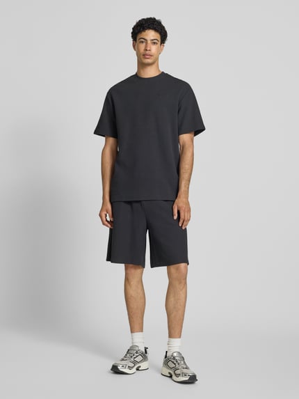 Männermodel trägt Oversized T-Shirt mit Strukturmuster und Logo-Stitching von KARL KANI aus Baumwoll-Mix, Oversized-Fit, Rundhalsausschnitt, Rückenlänge 75 cm in Größe M, Herren T-Shirt, Ganzkörperansicht von vorne.