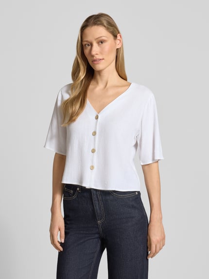 Vrouwenmodel draagt Hemdbluse aus Viskose-Mix mit Leinen-Anteil van Apricot in wit, recht model, V-hals, knoopsluiting, halve mouw, vooraanzicht bovenlichaam.