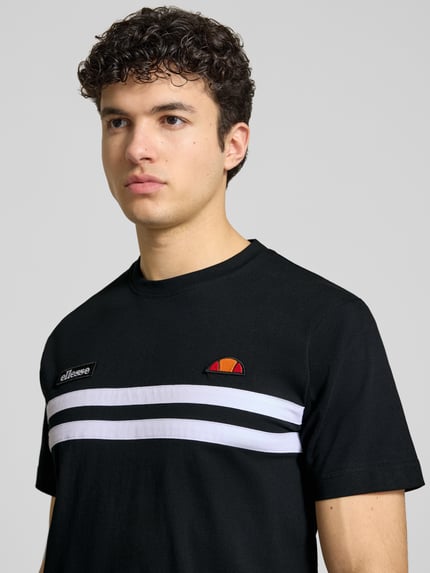 Mężczyzna model nosi T-Shirt mit Label-Stitchings Modell 'VENIRE' od Ellesse z czystej bawełny, czarne z białymi pasami, krój regular fit, okrągły dekolt, długość tyłu w rozmiarze M: 66 cm, zbliżenie na górną część ciała z przodu.