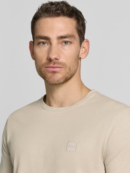 Männermodel trägt Regular Fit T-Shirt aus reiner Baumwolle Modell 'TALES' von BOSS Orange, Optik: Unifarben, Label-Patch, Kurzarm, Rundhals, Nahaufnahme Oberkörper.