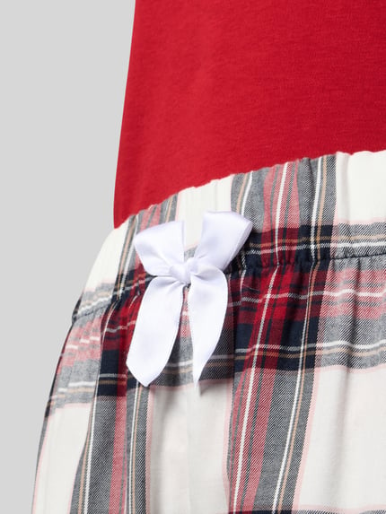 Frauenmodel trägt Pyjama mit Statement-Stitching Modell 'Kuschel-Momente' von LOUIS & LOUISA, rote, weiße und schwarze Baumwolle, Schleifen-Detail, Nahaufnahme Hüftbereich.