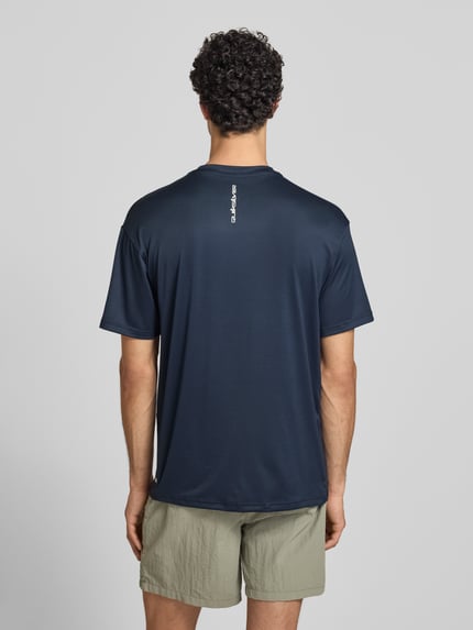 Männermodel trägt T-Shirt mit Rundhalsausschnitt und Logo von Quiksilver, Material-Mix mit Stretch-Anteil, Regular-Fit, Rückenlänge 75 cm, Ganzkörperansicht Rückansicht.