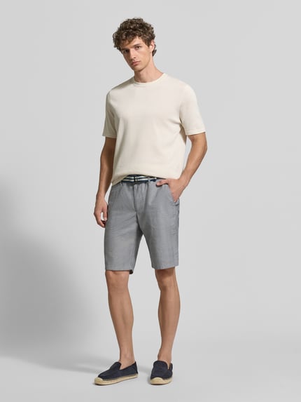 Männermodel trägt Bermudas mit französischen Eingrifftaschen und Gürtel von Christian Berg Men aus Baumwoll-Mix mit Stretch-Anteil, Ganzkörperansicht von vorne.