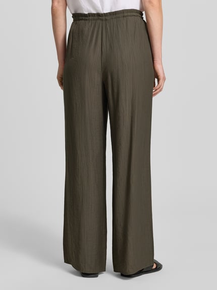 Vrouwenmodel draagt Wide Fit stoffen broek uit viscosemix model 'Marou' van OPUS met structuurpatroon, elastische band, binnenbeenlengte 78 cm bij maat 36, bandwijdte 113 cm bij maat 36, kleur olijfgroen, comfortbroekdesign, structuurtextuur, Ganzkörperansicht Rückansicht.