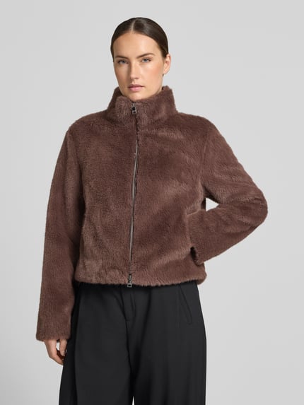 Frauenmodel trägt Jacke aus Kunstfell mit Zweiwege-Reißverschluss von Marc Cain in Braun, Regular Fit, Stehkragen, Nahaufnahme Oberkörper. Rückenlänge 51 cm, Schulterbreite 39 cm, Brustweite 48 cm, Ärmellänge 60 cm.