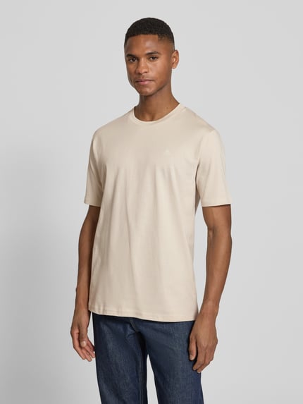 Männermodel trägt Regular Fit T-Shirt aus reiner Baumwolle von Marc O'Polo in Beige mit Logo-Print, Rundhals, kurzarm, Ganzkörperansicht von vorne.