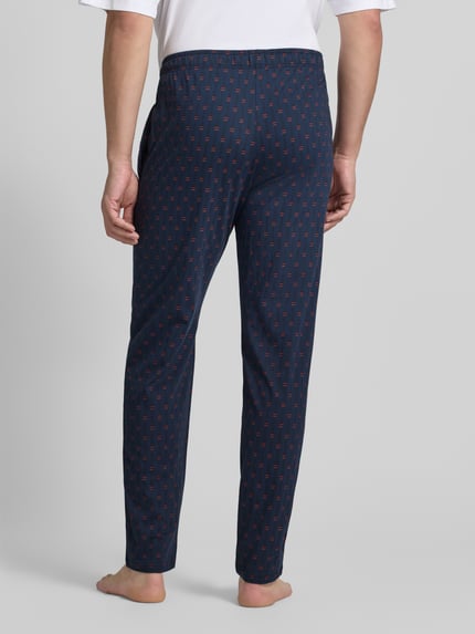 Männermodel trägt Sweatpants mit elastischem Bund von Schiesser in Dunkelblau mit rotem Muster, Reine Baumwolle, Lockerer-Schnitt, Ganzkörperansicht Rückansicht