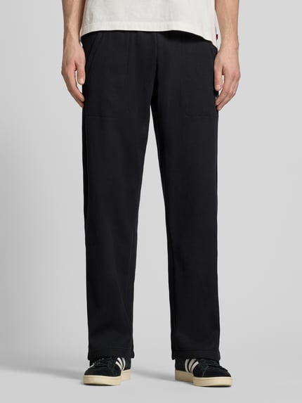 Männermodel trägt Straight Fit Sweatpants mit elastischem Bund Modell 'Essentials' von adidas Originals, schwarz, Strukturmuster, Baumwoll-Mix, Ganzkörperansicht von vorne.