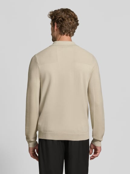 Mężczyzna nosi koszulkę polo Relaxed Fit z dodatkiem wełny model 'KN_Momentum-X PL' od BOSS Green w kolorze beżowym, gładka struktura, widok całej sylwetki od tyłu.