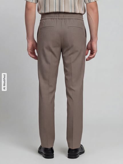 Männermodel trägt Relaxed Fit Sweatpants mit Viskose-Anteil von Lindbergh in Beige mit Bügelfalten, elastischer Bund, Ganzkörperansicht Rückansicht.