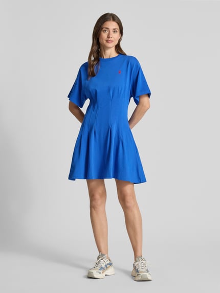 Frauenmodel trägt Leicht ausgestelltes Sweatkleid aus reiner Baumwolle von Polo Ralph Lauren in kräftigem Blau, Melange-Optik, Mini-Länge, Logo-Stitching, gelegte Falten, Rundhals, Kurzarm, Materialverarbeitung: Sweat, Ganzkörperansicht von vorne.