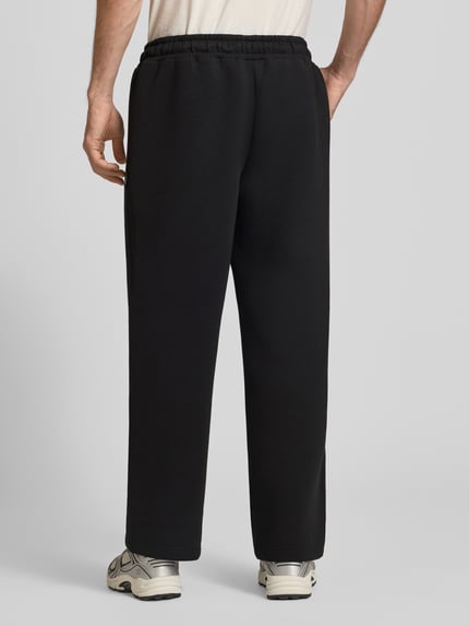 Männermodel trägt schwarze Regular Fit Sweatpants aus Material-Mix Modell 'BILL LEGACY' von JACK & JONES, elastischer Bund, Eingrifftaschen, Ganzkörperansicht Rückansicht, Herren Sweatpants Kontext.