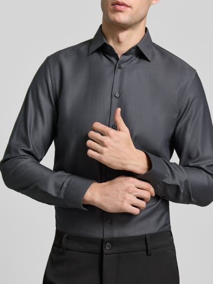 Männermodel trägt Slim Fit Businesshemd aus reiner Baumwolle von Jake*s in Unifarbe mit Kentkragen, einreihige Knopfleiste, Ganzkörperansicht von vorne.
