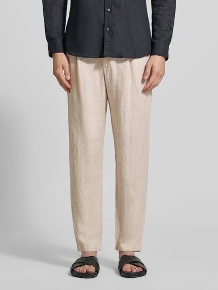 Männermodel trägt Tapered Fit Leinenhose mit Eingrifftaschen von MCNEAL in Beige, reine Leinen, Paspeltaschen, Bundweite 45 cm, Ganzkörperansicht von vorne.