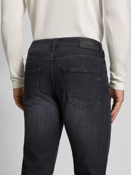 Männermodel trägt Slim Fit Jeans aus Baumwoll-Mix Modell 'Delaware' von BOSS in dunklem Grau, Herren Straight Fit Jeans, Ganzkörperansicht Rückansicht.