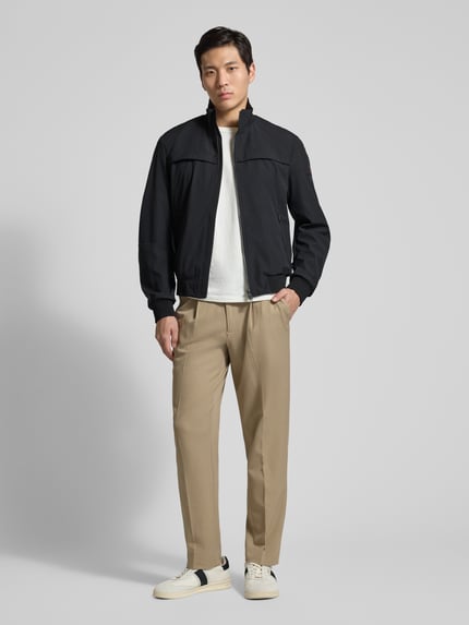 Männermodel trägt Jacke mit Stehkragen Modell 'POTOSI' von Peuterey, schwarz, glatte Textur, Regular Fit, Ganzkörperansicht von vorne.