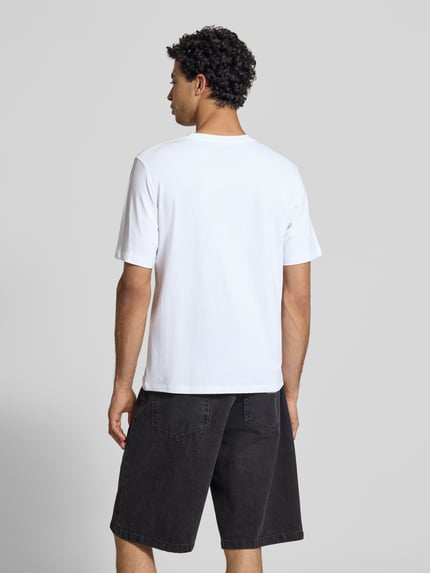 Męski model nosi męski t-shirt z nadrukiem z napisem model 'RHYERES' od Jack & Jones, biała bawełna woskowana, krój regular fit, okrągły dekolt, długość tyłu w rozmiarze M: 67 cm, widok całej sylwetki z tyłu.