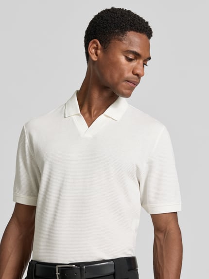 Männermodel trägt Regular Fit Poloshirt aus Baumwoll-Mix von s.Oliver RED LABEL in Weiß, feine Struktur, Nahaufnahme Oberkörper.