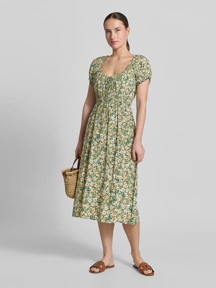 Vrouwenmodel draagt midi-jurk uit zuiver viscose met mouwen met ruches, getailleerd model van Apricot, all-over bloemenprint, ganzichaam vooraanzicht. Ruglengte maat S: 113 cm, borstwijdte: 29 cm, mouwlengte: 16 cm.
